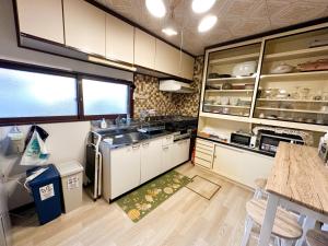 白老町にあるRenewal Chano Onsen House 温泉付きの白いキャビネット、シンク、テーブル付きのキッチンが備わります。