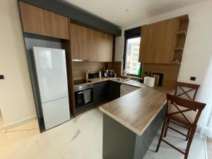 a kitchen with a white refrigerator and wooden cabinets at APARTMENT IVIL - ELIA RESIDENCE in Becici