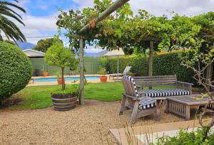 a wooden bench sitting in a garden next to a pool at Rawsonville House in Rawsonville