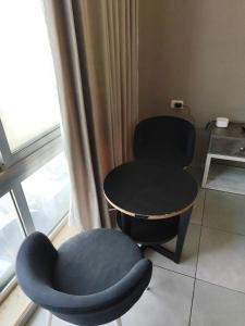2 sillas y una mesa en una habitación con ventana en Gentle Breeze Studio 2, en Amán