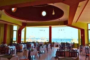 a restaurant with tables and chairs and a view of the ocean at Hostmark Zabargad Beach Resort in Abū Ghuşūn