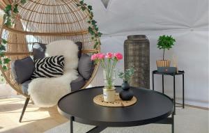 a room with a rattan chair and a table with flowers at Nice Home In Staffanstorp in Staffanstorp
