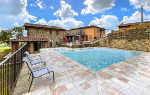einen Pool mit zwei Stühlen neben einem Gebäude in der Unterkunft 2 Bedroom Gorgeous Apartment In Castel Focognano in Castel Focognano