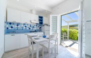 a kitchen with white cabinets and a table with chairs at Amazing Apartment In Framura With Kitchen in Framura