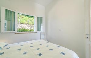 a white bedroom with a bed and two windows at Amazing Apartment In Framura With Kitchen in Framura