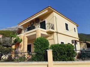 a yellow house with a balcony and bushes at LEONIDAS in Káto Vasilikí