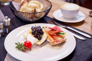 een wit bord met een broodje en een kopje koffie bij Panorama Samnaun in Samnaun +91 foto's