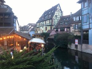 a group of people sitting at a restaurant next to a river at Le XVII - Au cœur de Colmar in Colmar