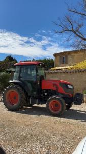 un tractor rojo estacionado en un estacionamiento de grava en Bastide Bellugue Maison d'hôtes réseau Bienvenue à La Ferme à 3 minutes de Lourmarin, en Cadenet