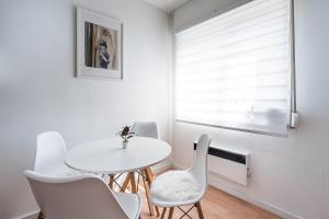 uma sala de jantar branca com uma mesa e cadeiras brancas em GuestReady - Modernity near Arrabida Shopping em Vila Nova de Gaia