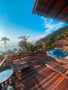 a deck with tables and chairs and a swimming pool at Pousada Éden in Angra dos Reis