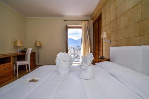 a bedroom with a large white bed with a window at Il Borgo Ospitale - Albergo Diffuso in Rotonda