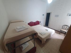 Cette petite chambre comprend deux lits et une chaise. dans l'établissement HOTEL IDEALE young people under 40, à Rimini