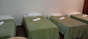 een kamer met 3 bedden en groene lakens bij Quarto em casa c/piscina in Ouro Fino