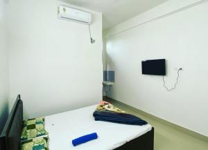 Habitación pequeña con cama y TV en la pared. en Hotel Abhinov, en Dibrugarh