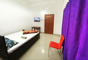 1 dormitorio con 1 cama y 1 silla roja en Hotel Abhinov, en Dibrugarh