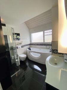 ein Badezimmer mit einer Badewanne, einem WC und einem Waschbecken in der Unterkunft Cozy Escape House 12 min away from Zurich Main Station in Ober Urdorf