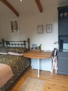 a table in a room with a bed and a table at The Honeypot Shepherds Hut in Ross on Wye