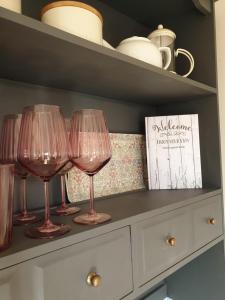 three wine glasses sitting on top of a dresser at The Honeypot Shepherds Hut in Ross on Wye