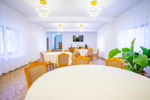 a dining room with tables and chairs and a tv at Casa Zuz in Gura Humorului