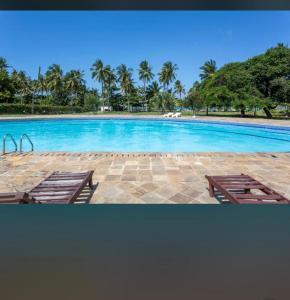 a large swimming pool with two chairs and palm trees at Owen Studio in Diani Beach