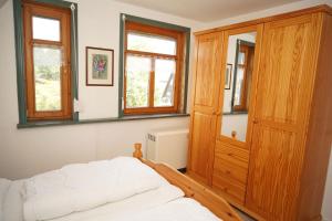 een slaapkamer met een bed, een houten kast en ramen bij Ferienhaus mit viel Platz in Strandnaehe in Damp
