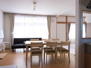 a dining room with a table and chairs and a couch at FURANO BnB in Furano