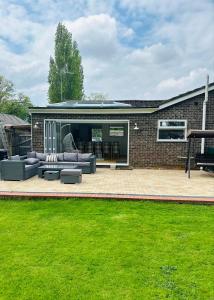 a patio with couches and chairs in front of a building at "Tranquil Village Hideaway Bungalow"near Kings Lynn in Kings Lynn