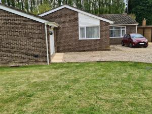 a red car parked in front of a house at "Tranquil Village Hideaway Bungalow"near Kings Lynn in Kings Lynn