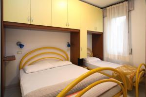 two beds in a room with yellow cabinets at Villa Medea in Rosolina Mare