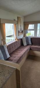 ein großes Sofa in einem Zimmer mit Fenster in der Unterkunft the poplars lyons robin hood in Meliden