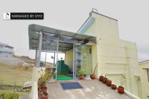 une maison avec un garage avec des plantes en pot sur une terrasse dans l'établissement Super Collection O Kodai Mist Perumpallam - Managed by Company, à Kodaikānāl