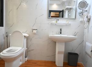 a white bathroom with a toilet and a sink at GRAND Hôtel Akwa in Douala +16 photos