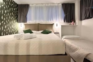 een slaapkamer met 2 bedden met witte lakens en groene kussens bij SaliS28 MM3 Affori Centro in Milaan
