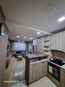 a kitchen with wooden cabinets and a living room at Happy 1 in Tbilisi City