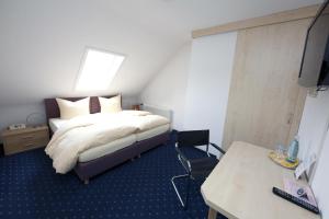 a bedroom with a bed and a desk and a television at Hotel Restaurant Engel in Pfaffenweiler