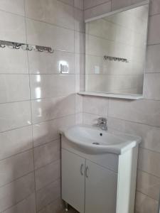 a white bathroom with a sink and a mirror at Demir Apartmani in Donji Štoj