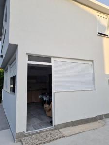a white house with a sliding garage door at Demir Apartmani in Donji Štoj