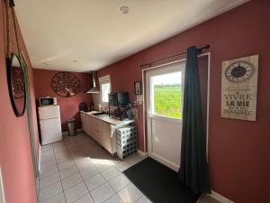 a kitchen with red walls and a kitchen with a window at Gîte de la Prévosserie in Rinxent