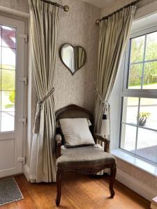 einen Stuhl in einem Zimmer mit Vorhängen und einem Spiegel in der Unterkunft The Lodge Donegal Town in Donegal