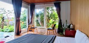 um quarto com uma cama e uma grande janela em Nature Homes Đà Lạt em Da Lat