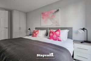 um quarto com uma cama grande e almofadas cor-de-rosa em 2bdr Super King Suite em Manchester