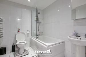 uma casa de banho branca com um WC e um lavatório em 2bdr Super King Suite em Manchester