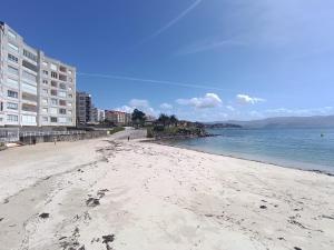 einen Sandstrand mit Gebäuden und dem Meer in der Unterkunft Apartamento Playa Panadeira in Sanxenxo