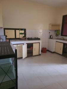 a kitchen with white cabinets and a white tile floor at Picho two bedroom apartment in Malindi