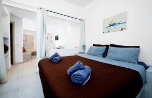 a bedroom with a large bed with blue towels on it at Angel Santorini Residences in Vourvoulos