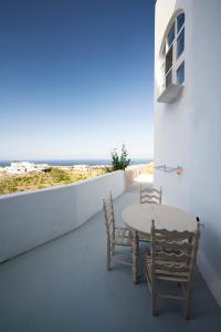 Angel Santorini Residences في Vourvoúlos: طاولة وكراسي على شرفة مطلة على المحيط