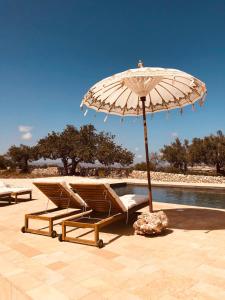 un par de sillas y una sombrilla junto a una piscina en Casa Imayah, en Noto