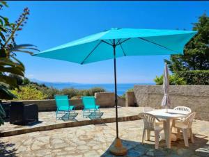 LOCATION CORSE في Canari: طاولة وكراسي مع مظلة زرقاء