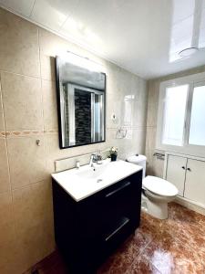 een badkamer met een wastafel, een toilet en een spiegel bij Cardenales in Barcelona